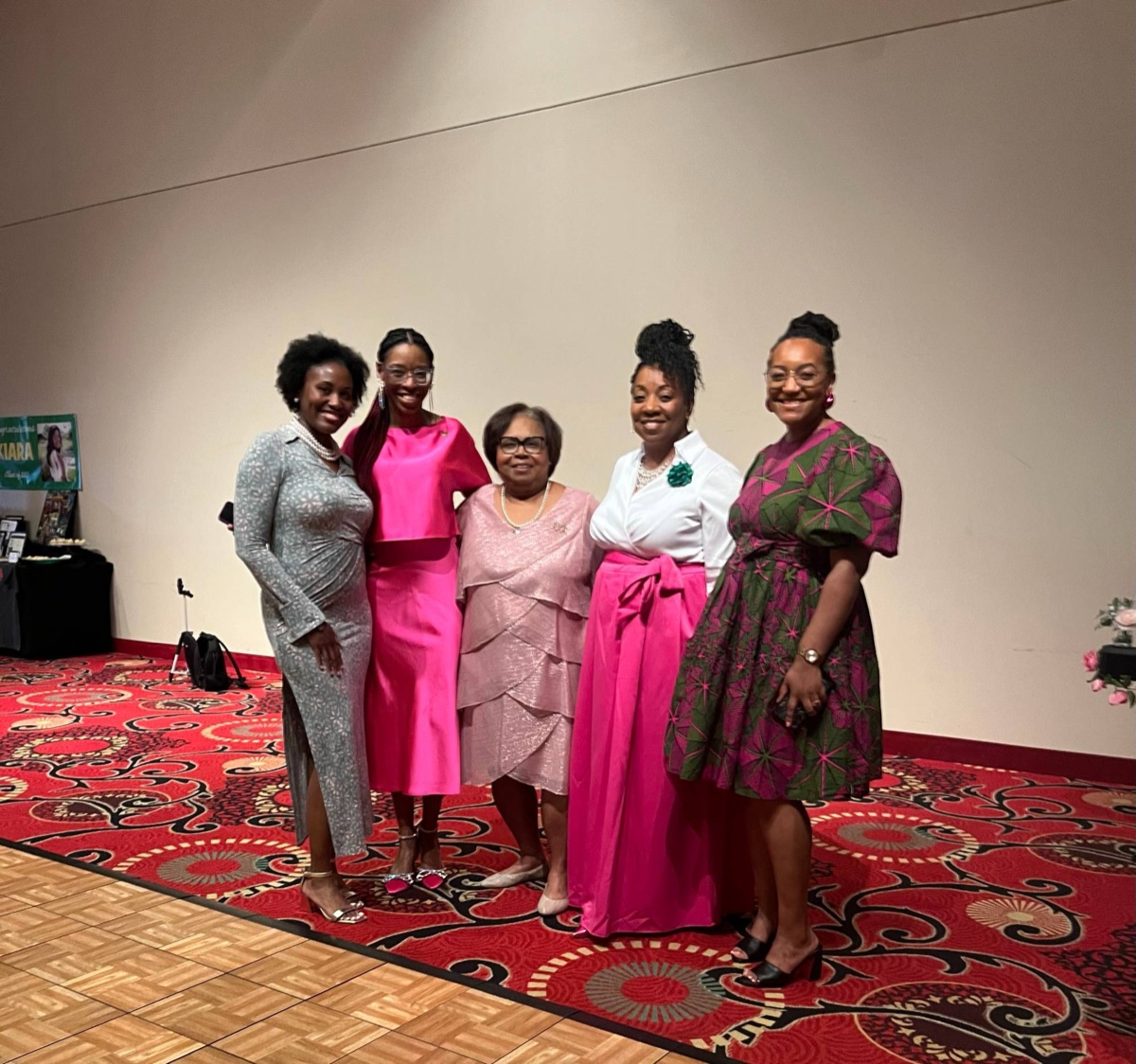 Five sorors in pink, white, and green at a banquet