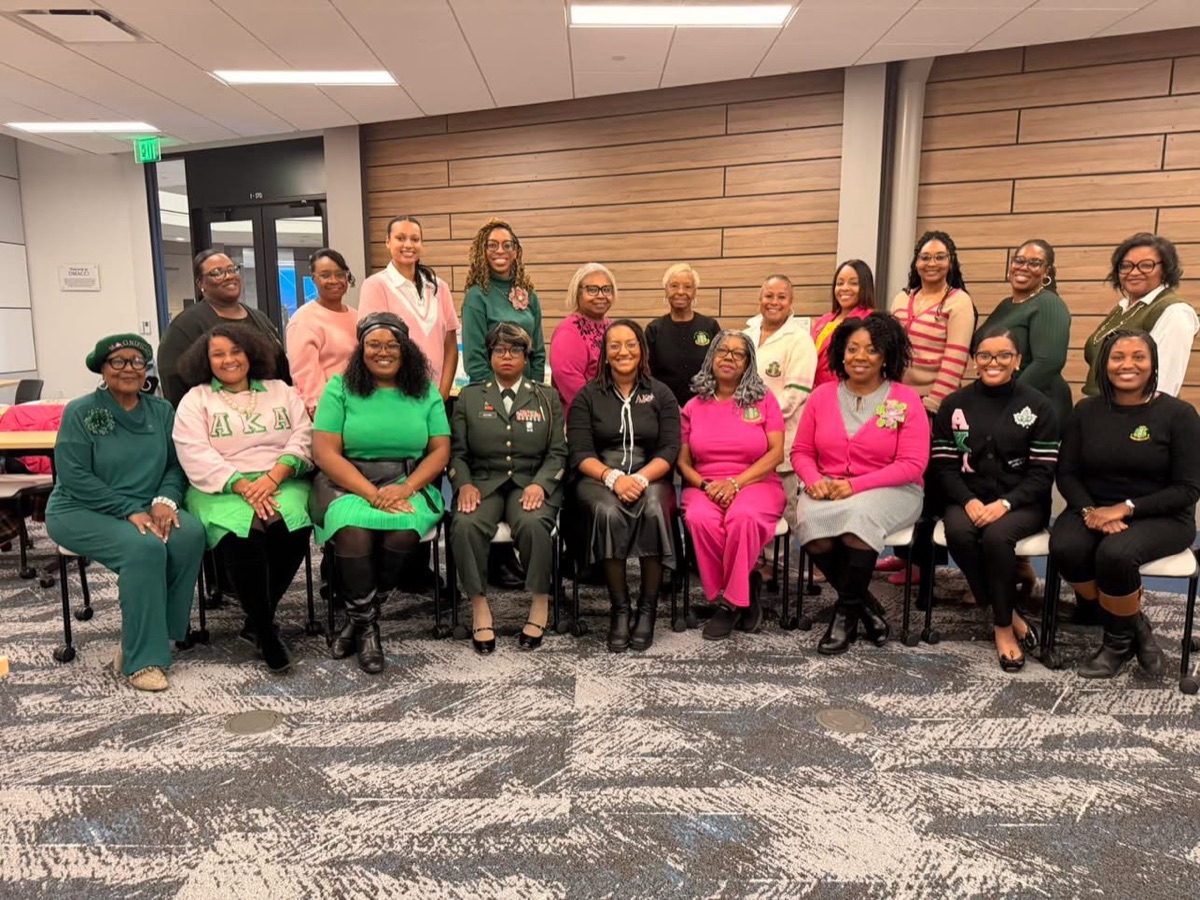Iota Zeta Omega sorors in pink, green, and black gathered for a group photo