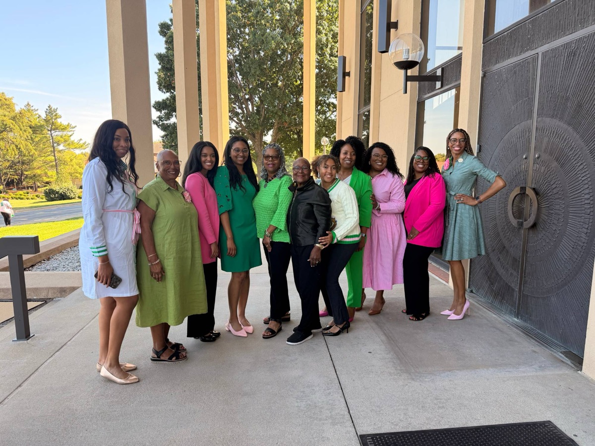 Sorors in pink and green outside a building with tall columns