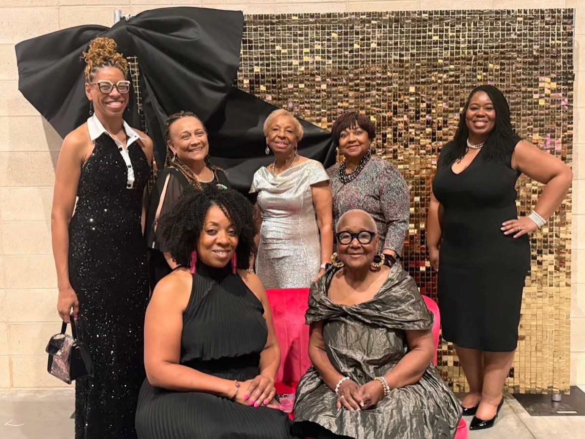 Sorors in formal attire in front of a gold sequin wall
