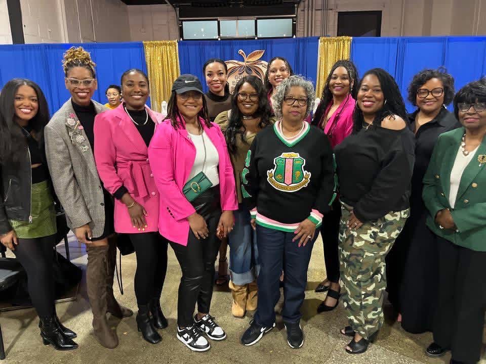 Iota Zeta Omega sorors together in front of a blue and gold backdrop